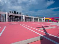 a basketball court with many colored lines in front of a building with two ladders