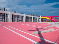 a basketball court with many colored lines in front of a building with two ladders