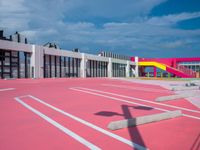 a basketball court with many colored lines in front of a building with two ladders