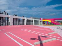 a basketball court with many colored lines in front of a building with two ladders