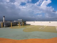 a parking lot with green grass and yellow poles in the center, on a cloudy day