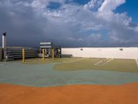 a parking lot with green grass and yellow poles in the center, on a cloudy day