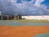 a parking lot with green grass and yellow poles in the center, on a cloudy day