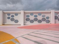 a garage with pink walls and blue windows on a cloudy day with sky clouds above