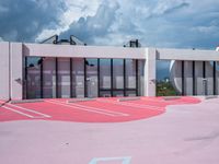 red and white painted parking lot for the outside of a building with gray and black clouds above