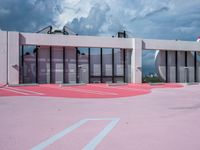 red and white painted parking lot for the outside of a building with gray and black clouds above
