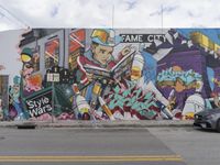 the car sits in front of a wall of graffiti near a street light and buildings