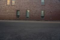 the side of a building with two windows on one of them and a man riding a skateboard