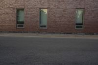 the side of a building with two windows on one of them and a man riding a skateboard