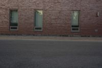 the side of a building with two windows on one of them and a man riding a skateboard