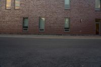 the side of a building with two windows on one of them and a man riding a skateboard