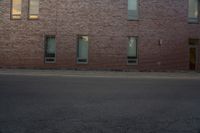 the side of a building with two windows on one of them and a man riding a skateboard