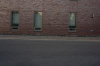 the side of a building with two windows on one of them and a man riding a skateboard