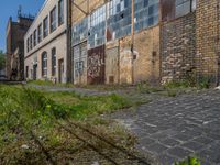 an old brick building sitting next to a sidewalk and field of grass with buildings in the background