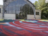 a painting on the ground near a building with many windows and grass in front of it