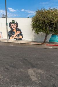 a person riding down the side of a road near a wall with a mural of a man and a woman on it