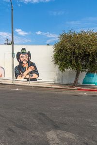 a person riding down the side of a road near a wall with a mural of a man and a woman on it