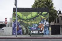 a graffiti wall depicting an assortment of characters painted on it next to a park bench