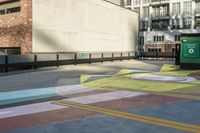 a woman sitting on the sidewalk on a skateboard painting in the street, a large building with windows behind it