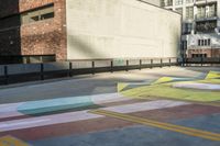 a woman sitting on the sidewalk on a skateboard painting in the street, a large building with windows behind it