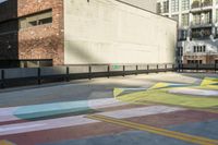 a woman sitting on the sidewalk on a skateboard painting in the street, a large building with windows behind it