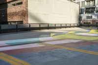 a woman sitting on the sidewalk on a skateboard painting in the street, a large building with windows behind it