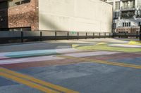 a woman sitting on the sidewalk on a skateboard painting in the street, a large building with windows behind it