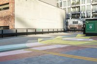 a woman sitting on the sidewalk on a skateboard painting in the street, a large building with windows behind it