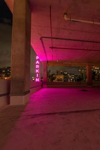 the cityscape is lit pink against the night sky as it stands empty in the parking garage