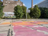 the basketball court is painted with the colors pink, orange, and blue, in a brick building