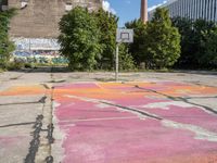 the basketball court is painted with the colors pink, orange, and blue, in a brick building