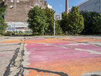 the basketball court is painted with the colors pink, orange, and blue, in a brick building