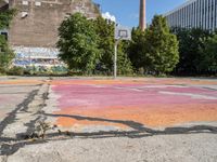 the basketball court is painted with the colors pink, orange, and blue, in a brick building