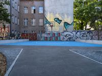 a basketball court in front of an apartment building with graffiti on it's wall