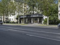 a bus parked on the side of the street in front of a building and many trees