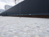 a white and black dog runs near the fence on an outdoor area with a building in the background
