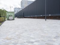 a white and black dog runs near the fence on an outdoor area with a building in the background