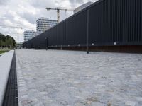 a white and black dog runs near the fence on an outdoor area with a building in the background
