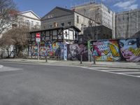 the street in front of the graffiti covered building is empty and empty, but has two rows