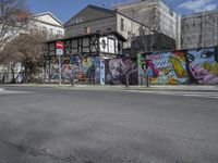 the street in front of the graffiti covered building is empty and empty, but has two rows