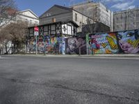 the street in front of the graffiti covered building is empty and empty, but has two rows