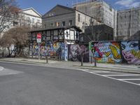 the street in front of the graffiti covered building is empty and empty, but has two rows