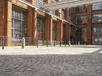 a brick courtyard outside the building with a horse statue behind glass doors and windows on the outside