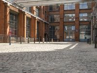 a brick courtyard outside the building with a horse statue behind glass doors and windows on the outside