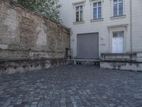 there is a bench and a door near a large building with windows in the back