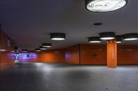 the view from inside a public bathroom with ceiling lights and orange tiles and a man with a suitcase