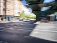 a street with two trains on it and a few people walking under an overpass