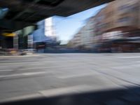 a street with two trains on it and a few people walking under an overpass