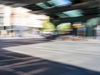 a street with two trains on it and a few people walking under an overpass