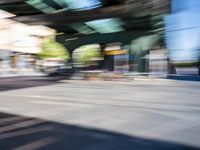 a street with two trains on it and a few people walking under an overpass